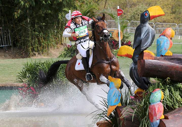 Japan’s Yoshiaki Oiwa, riding The Duke of Cavan, jumps out of the water during the equestrian preliminary event on August 8, 2016.