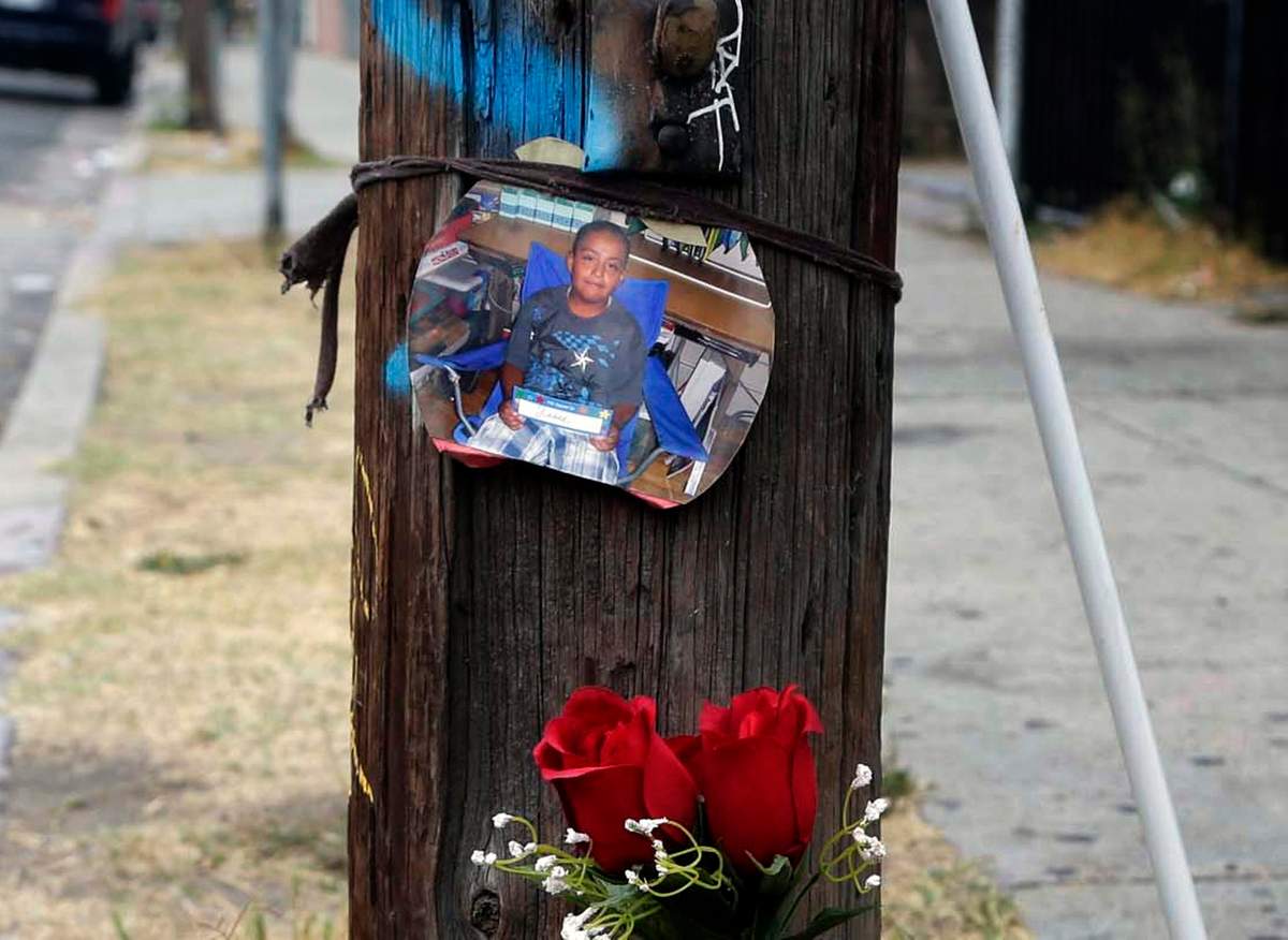 A photo and flowers are left at a street side memorial for a teen who was fatally shot by police in the Boyle Heights section of Los Angeles on Wednesday, Aug. 10, 2016. 