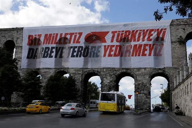 Vehicles pass the Valens Aqueduct with a banner reading ''We are the nation, we won't let Turkey fall to coups and terrorism'' in Istanbul, on Monday, Aug. 15, 2016.