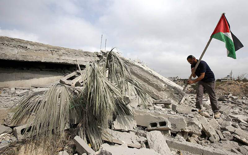 A Palestinian plants a Palestinian flag amongst the rubble of a home after it was demolished by the Israeli army with explosives in the West Bank village of Dura on August 30, 2016.