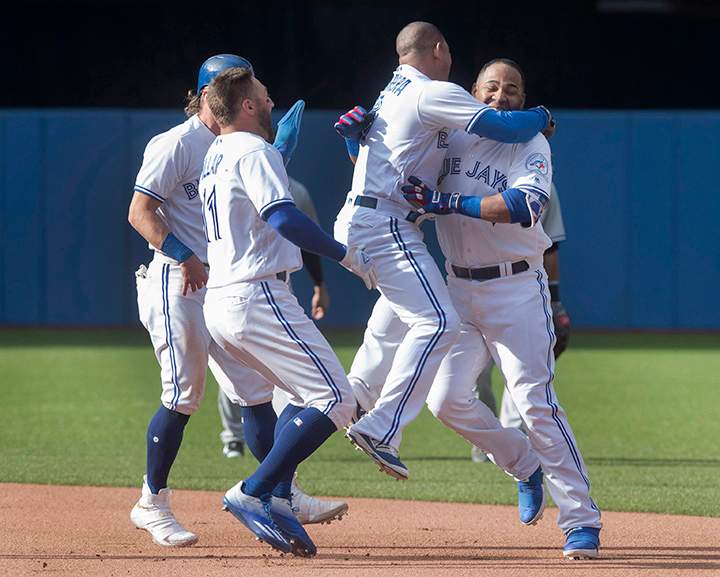 Toronto Blue Jays Edwin Encarnacion (right) is mobbed by teammates (left to right) Josh Donaldson, Kevin Pillar and Ezequiel Carrera after he drove in the winning run in the ninth inning of their American League MLB baseball game against the New York Yankees in Toronto Sunday.