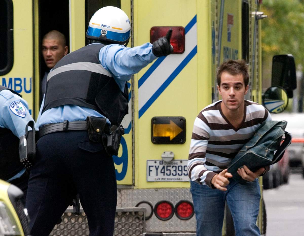 Police direct a man running to take cover during a shooting incident at Dawson College in Montreal, Wednesday, Sept. 13, 2006.