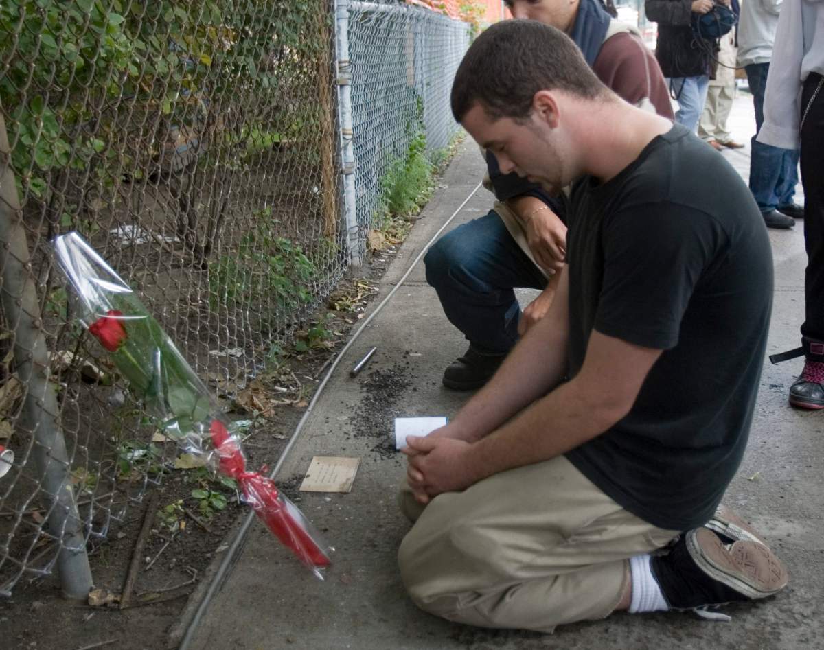 Chris Neill pauses for a short prayer after putting a rose against the fence at Dawson College in Montreal Thursday Sept. 14, 2006. Neill's friend Liz Distalo was shot Wednesday by a gunman who went on a rampage in the college.