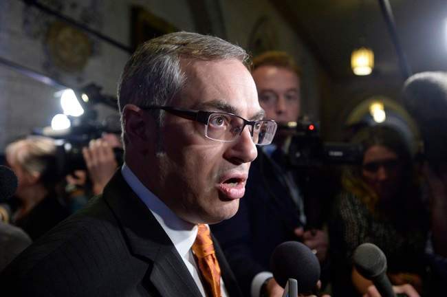 Treasury Board President Tony Clement fields questions in the foyer outside the House of Commons in Ottawa, Monday, May 11, 2015. 