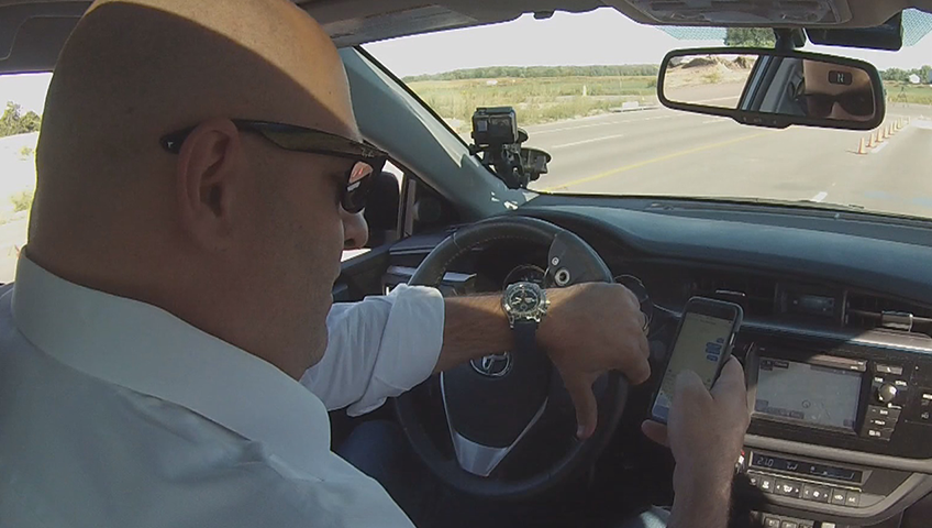 A man checks his cellphone while driving.