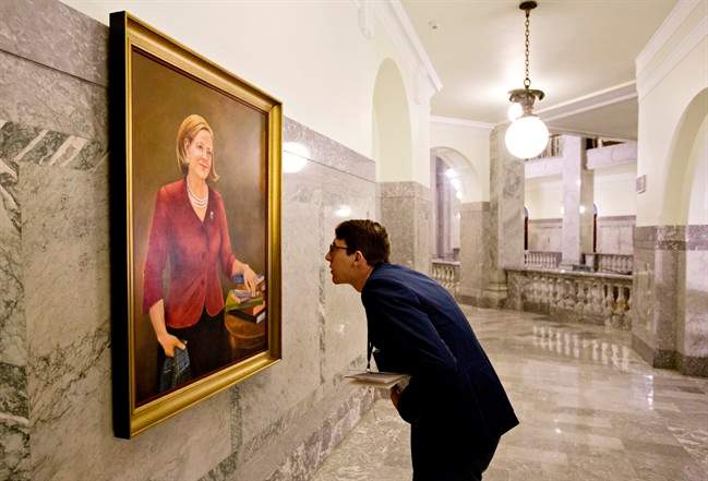 A government worker examines a painting of former Alberta Premier Alison Redford hanging in the Alberta Legislature amongst past premiers, in Edmonton on Thursday, September 8, 2016.