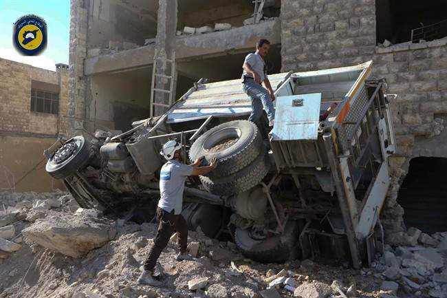 In this photo provided by the Syrian Civil Defense group known as the White Helmets, rescue workers remove a destroyed ambulance after airstrikes in Ansari neighborhood in the rebel-held part of eastern Aleppo. Friday, Sept. 23, 2016.
