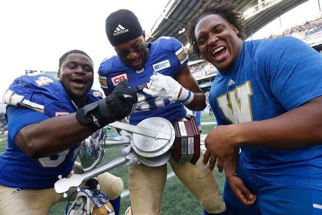 Winnipeg Blue Bombers' Euclid Cummings, Gerrard Sheppard and Padric Scott strum the Banjo Bowl after defeating the Saskatchewan Roughriders in CFL action in Winnipeg Saturday, September 10, 2016.