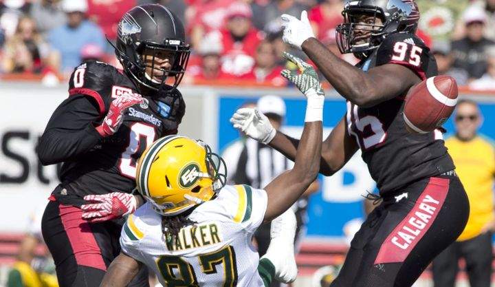 Edmonton Eskimos' Derel Walker, centre, loses the ball after taking a hard hit from Calgary Stampeders' Ciante Evans, left, and Ja'Gared Davis during second half CFL Labour Day Classic football action in Calgary, Alberta on Monday, Sept. 5, 2016. 
