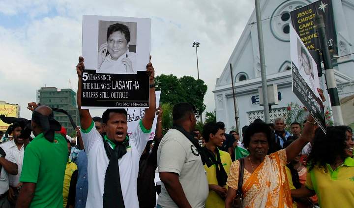 In this Jan. 28, 2014 file photo, a protester holds a portrait of Lasantha Wickrematunge, a journalist who was killed, during a protest in Colombo, Sri Lanka. A Sri Lankan court on Thursday gave permission to police to exhume the remains of the newspaper editor killed seven years ago for a fresh investigation.