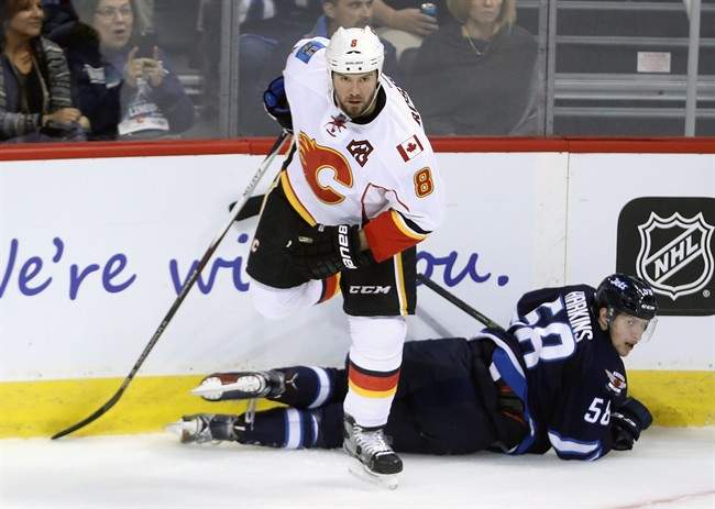 Calgary Flames' Nicklas Grossman (8) steps over Winnipeg Jets' Jansen Harkins (58) during first period pre-season NHL hockey in Winnipeg, Tuesday, September 27, 2016.