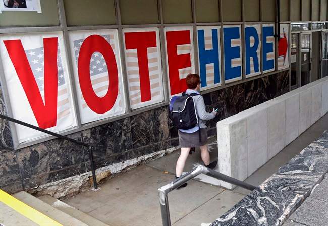 In this Sept. 23, 2016 file photo, a woman passes a large sign before voting in Minneapolis. Americans will vote for much more than a  president next Tuesday.