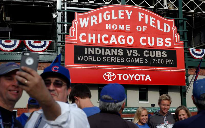 Fans take pictures in front of the Wrigley Field marquee before Game 3 of the Major League Baseball World Series between the Chicago Cubs and the Cleveland Indians, Friday, Oct. 28, 2016, in Chicago.