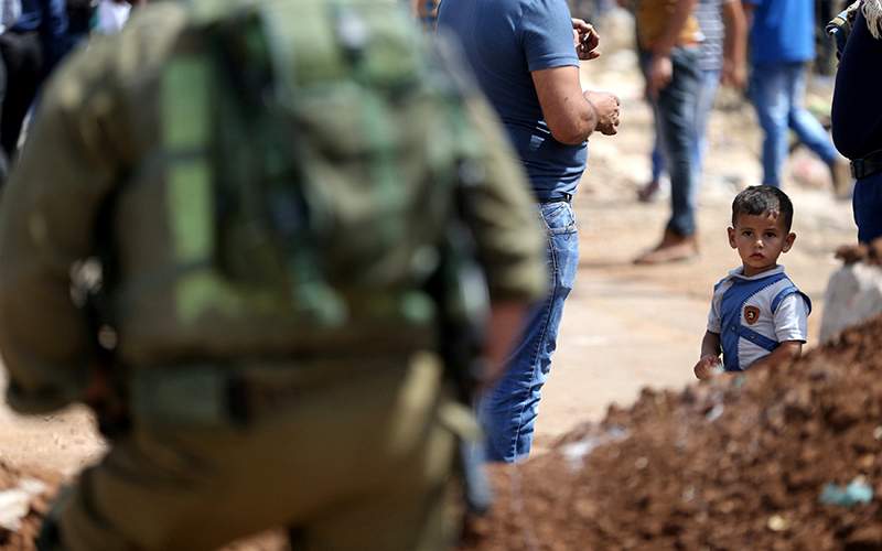An Israeli soldier stands guard as a Palestinian boys looks on during a protest against the closure of the entrance of the West Bank village of Beta, near Nablus September 23, 2016. REUTERS/Mohamad Torokman.