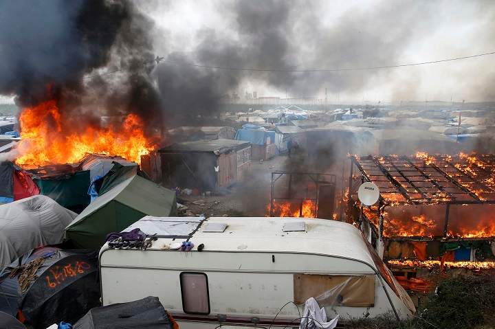 Smoke and flames fill the sky from burning makeshift shelters in the “Jungle” on the third day of the evacuation and transfer of migrants to reception centers in France, as part of the dismantlement of the camp in Calais, France, October 26, 2016. REUTERS/Pascal Rossignol