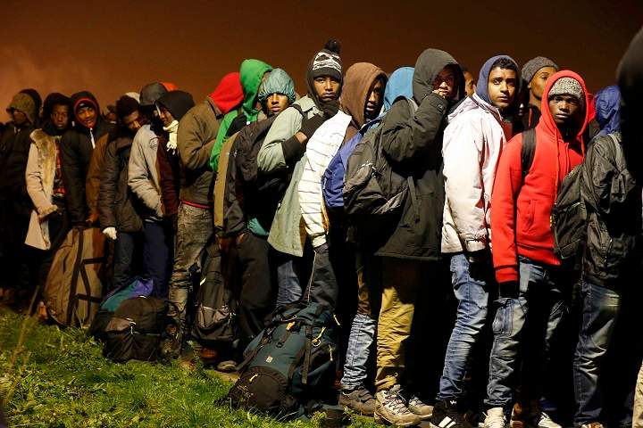 Migrants with their belongings queue as their evacuation and transfer to reception centers in France, and the dismantlement of the camp called the “Jungle” in Calais, France, starts October 24, 2016. (REUTERS/Pascal Rossignol)