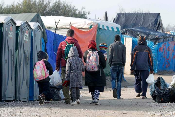 Migrants carry their belongings as they walk in an alley near tents and makeshift shelters on the eve of the evacuation and dismantlement of the camp called the “Jungle” in Calais, France, October 23, 2016. REUTERS/Philippe Wojazer