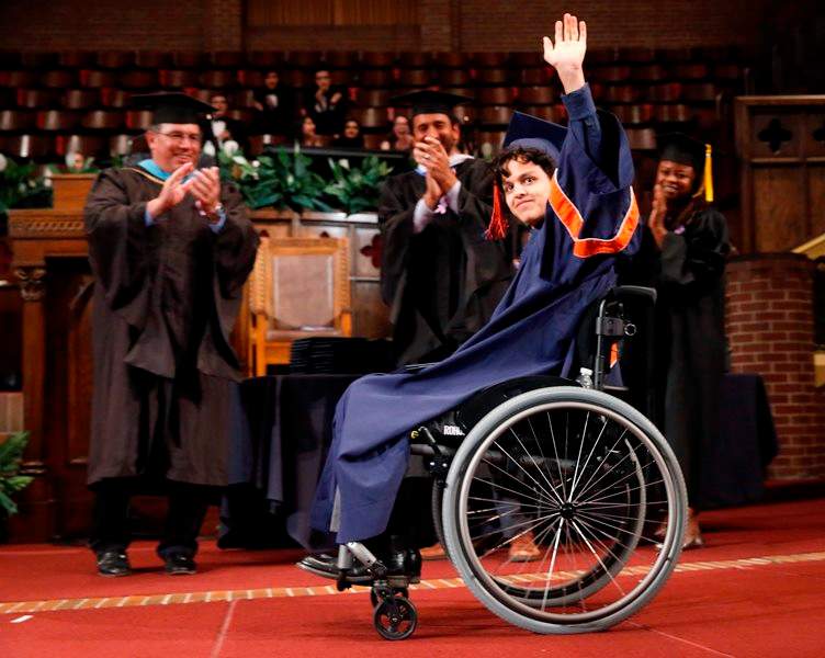 In this Monday, June 13, 2016 photo, Jonathan Annicks waves to a cheering crowd as he graduates from high school in Chicago.