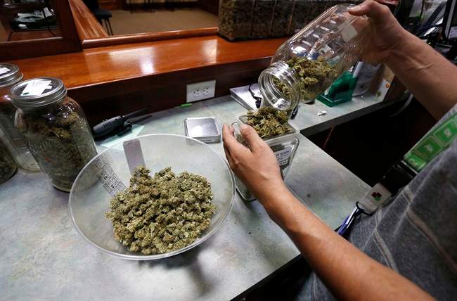 An employee places marijuana for sale into glass containers at The Station, a retail and medical cannabis dispensary, in Boulder, Colo., Thursday, Aug. 11, 2016.