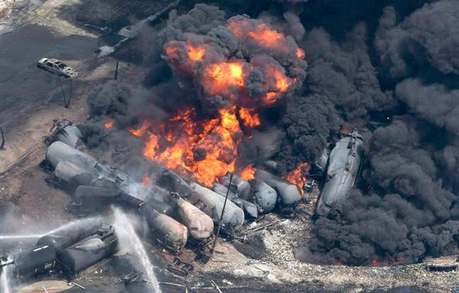 Smoke rises from railway cars that were carrying crude oil after derailing in downtown Lac-Megantic, Que., on July 6, 2013. A Quebec Superior Court judge is allowing changes to the class action lawsuit in the 2013 Lac-Megantic disaster.
