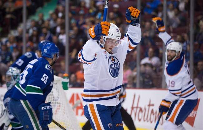 Edmonton Oilers' Drake Caggiula, centre, and Patrick Maroon, back right, celebrate Caggiula's goal against Vancouver Canucks' goalie Ryan Miller, back left, during the first period of a pre-season NHL hockey game in Vancouver, B.C., on Wednesday September 28, 2016.