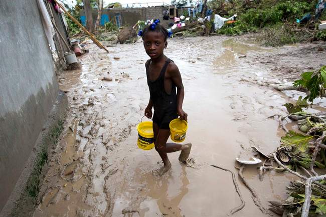 A girl lugs buckets of drinking water after the passing of Hurricane Matthew in Les Cayes, Haiti, Thursday, Oct. 6, 2016. Canada has earmarked $54 million over five years for Haiti, to help with immediate disaster relief as well as long-term agricultural initiatives.