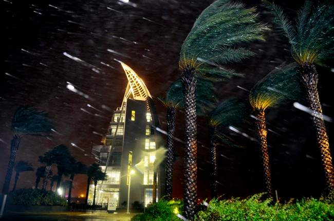Trees sway from heavy rain and wind from Hurricane Matthew in front of Exploration Tower early Friday, Oct. 7, 2016 in Cape Canaveral, Fla. Matthew weakened slightly to a Category 3 storm with maximum sustained winds near 120 mph, but the U.S. National Hurricane Center says it's expected to remain a powerful hurricane as it moves closer to the coast. (Craig Rubadoux/Florida Today via AP)