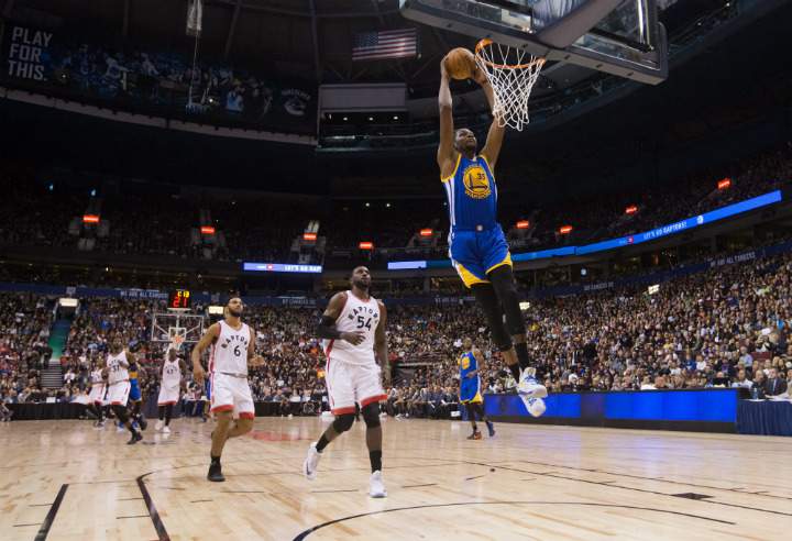 Golden State Warriors' Kevin Durant, right, dunks as Toronto Raptors' Patrick Patterson (54) and Cory Joseph (6) watch during first half pre-season NBA basketball action in Vancouver, B.C., on Saturday October 1, 2016. 