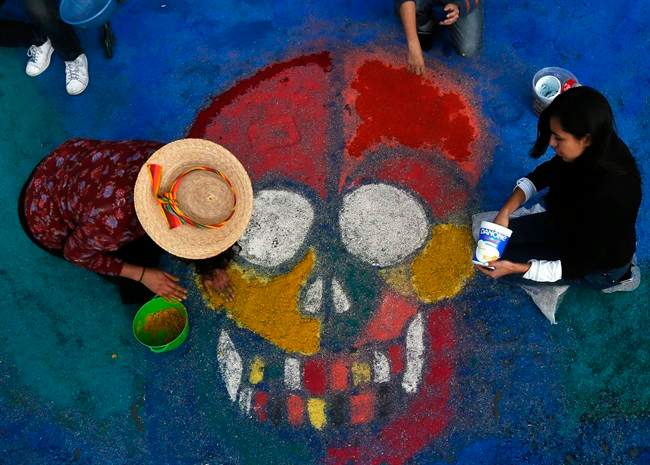 Residents create a sawdust representation of a skull during Day of the Dead festivities in Mexico City, Thursday, Oct. 27, 2016. The holiday honors the dead as friends and families gather in cemeteries to decorate their loved ones' graves and hold vigil through the night on Nov. 1 and 2. 
