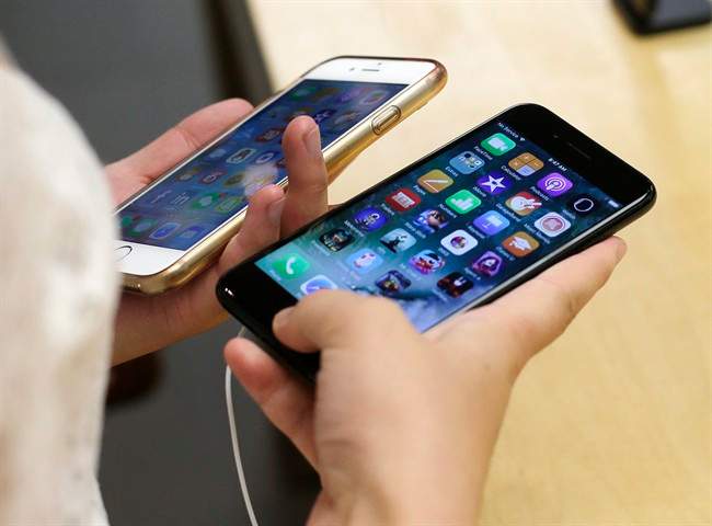 In this Sept. 16, 2016, file photo, Lisa Gao, from Chicago, compares a new jet black iPhone 7, right, with her iPhone 6 at an Apple Store in Chicago. 