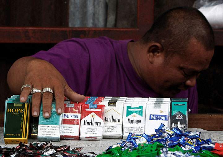 A vendor displays cigarettes as he waits for customers along a busy street in Manila.