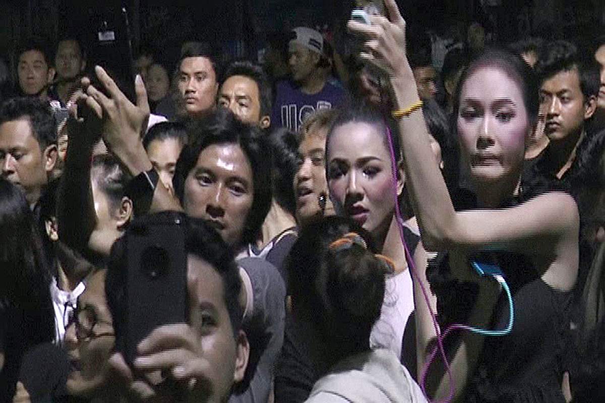 In this Friday, Oct. 14, 2016 image made from video, people gather outside a soy milk shop on the Thai resort island of Phuket. 