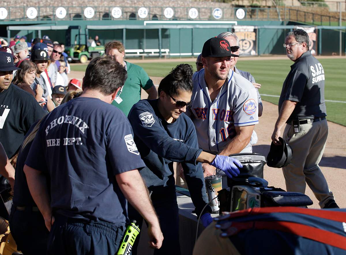 Scottsdale Scorpions outfielder Tim Tebow, center, comforts a fan, on ground, who was suffering a seizure, following Tebow's debut against the Glendale Desert Dogs in a baseball game Tuesday, Oct. 11, 2016, during the Arizona Fall League in Glendale, Ariz.