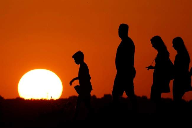 FILE - In this July 21, 2016, file photo, the sun sets beyond visitors to Liberty Memorial as the temperature hovers around 100 degrees in Kansas City, Mo.