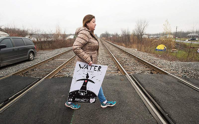 A member of the Kahnawake Mohawk community walks across a rail track on the Kahnawake reserve near Montreal, Wednesday, November 16, 2016, in support of opponents of the Dakota Access Pipeline.