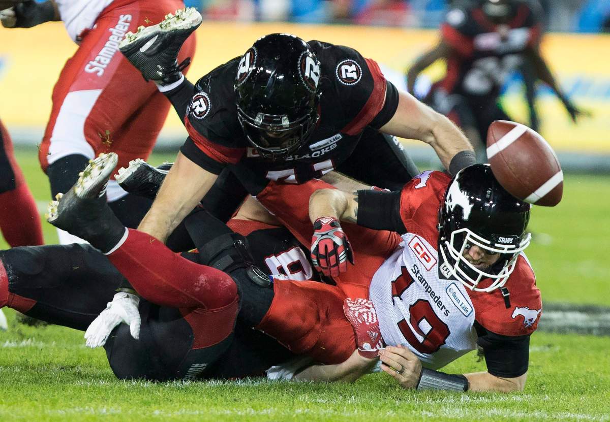 Calgary Stampeders quarterback Bo Levi Mitchell is sacked by Ottawa Redblacks defensive lineman Zack Evans, bottom and defensive end Arnaud Gascon-Nadon during third quarter CFL Grey Cup action Sunday, November 27, 2016 in Toronto. 