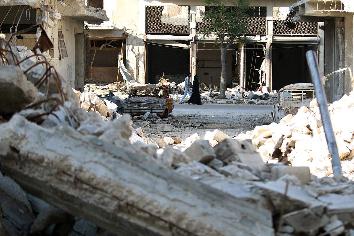 People walk past rubble of damaged buildings in a rebel-held besieged area in Aleppo, Syria November 6, 2016. 