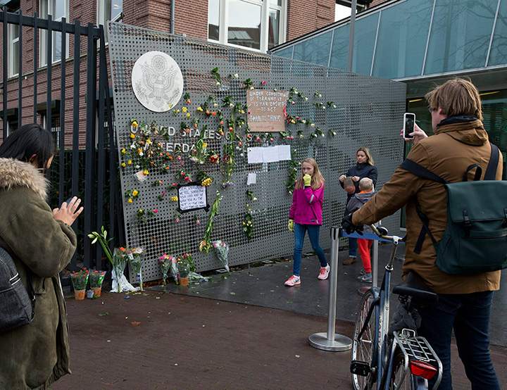 People take pictures of flowers and signs put up in reaction to the outcome of the U.S. presidential election at the entrance to the U.S. consulate in Amsterdam, Netherlands, Thursday, Nov. 10, 2016.