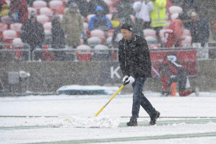 A worker helps to remove snow on the playing field before first half CFL eastern final action between the Ottawa RedBlacks and Edmonton Eskimos, in Ottawa on Sunday, November 20, 2016. 