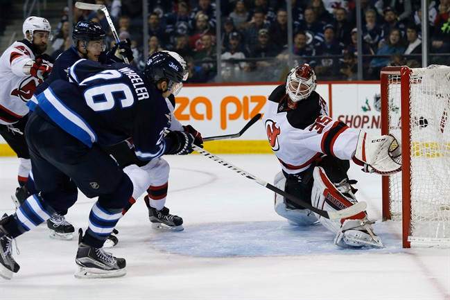 Winnipeg Jets' Blake Wheeler (26) scores on New Jersey Devils goaltender Cory Schneider (35) as John Moore (2) defends during second period NHL action in Winnipeg on Tuesday, November 29, 2016. 