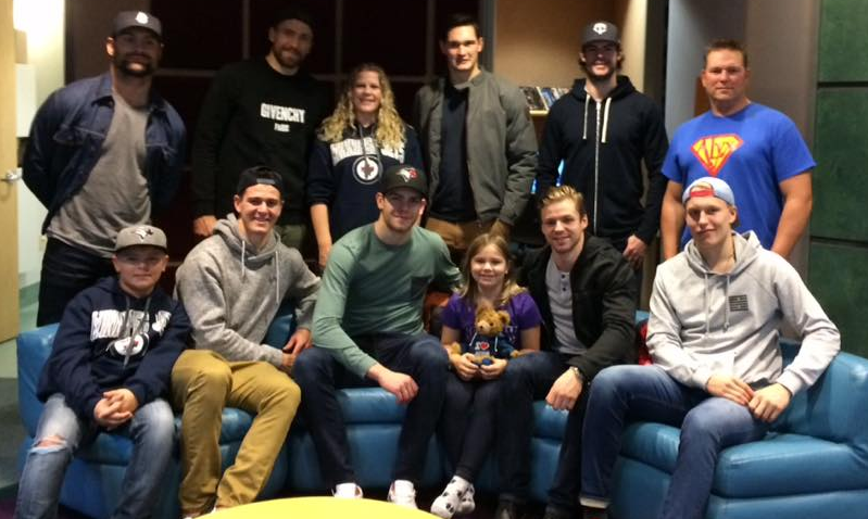 Adam Lowry, Mark Stuart, Blake Wheeler, Michael Hutchinson, and Patrik Laine greet Alyx Delaloye. 