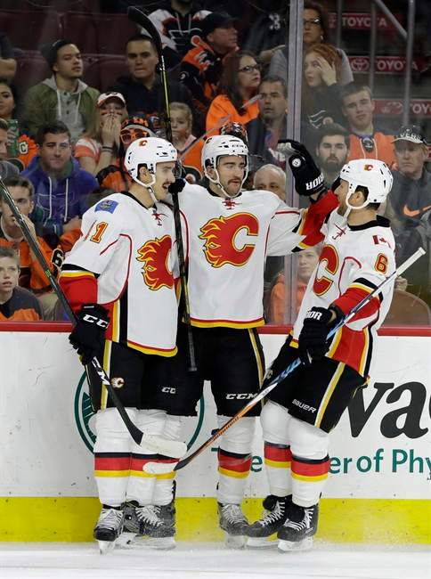 Calgary Flames' Mikael Backlund, from left, TJ Brodie and Dennis Wideman celebrate after Brodie's goal during the first period of an NHL hockey game against the Philadelphia Flyers, Sunday, Nov. 27, 2016, in Philadelphia. 
