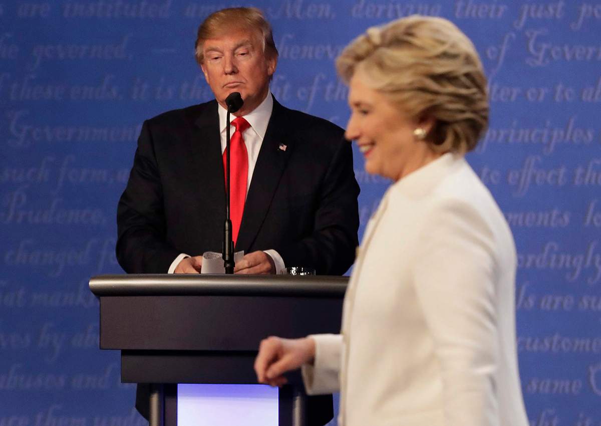 In this Oct. 19, 2016 file photo, Republican presidential nominee Donald Trump waits behind his podium as Democratic presidential nominee Hillary Clinton makes her way off the stage following the third presidential debate at UNLV in Las Vegas. 