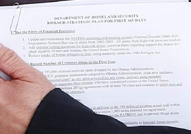 President-elect Donald Trump and Kansas Secretary of State, Kris Kobach, meet at the Trump National Golf Club Bedminster clubhouse, Sunday, Nov. 20, 2016, in Bedminster, N.J.. The documents Kobach is holding offers a glimpse of his plan for the Department of Homeland Security.