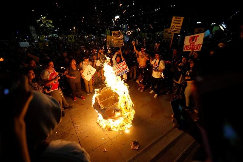 A Donald Trump pinata is burned by people protesting the election of Republican Donald Trump as the president of the United States in downtown Los Angeles, California U.S., November 9, 2016. REUTERS/Mario Anzuoni