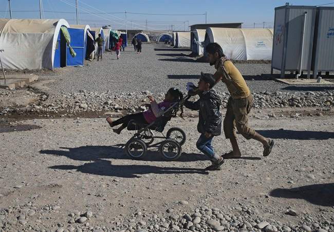 An Iraqi man who fled the fighting between Islamic State militants and the Iraqi forces, carries a handicapped girl at a camp for internally displaced people, in Khazer east of Mosul, Iraq, Monday, Nov. 21, 2016. Iraqi troops fighting Islamic State militants in the eastern outskirts of Mosul regrouped Monday in the city's neighborhoods they recently retook from the extremist group, conducting house-to-house searches and looking for would-be suicide car bombs, a top Iraqi commander said. (AP Photo/Hussein Malla).