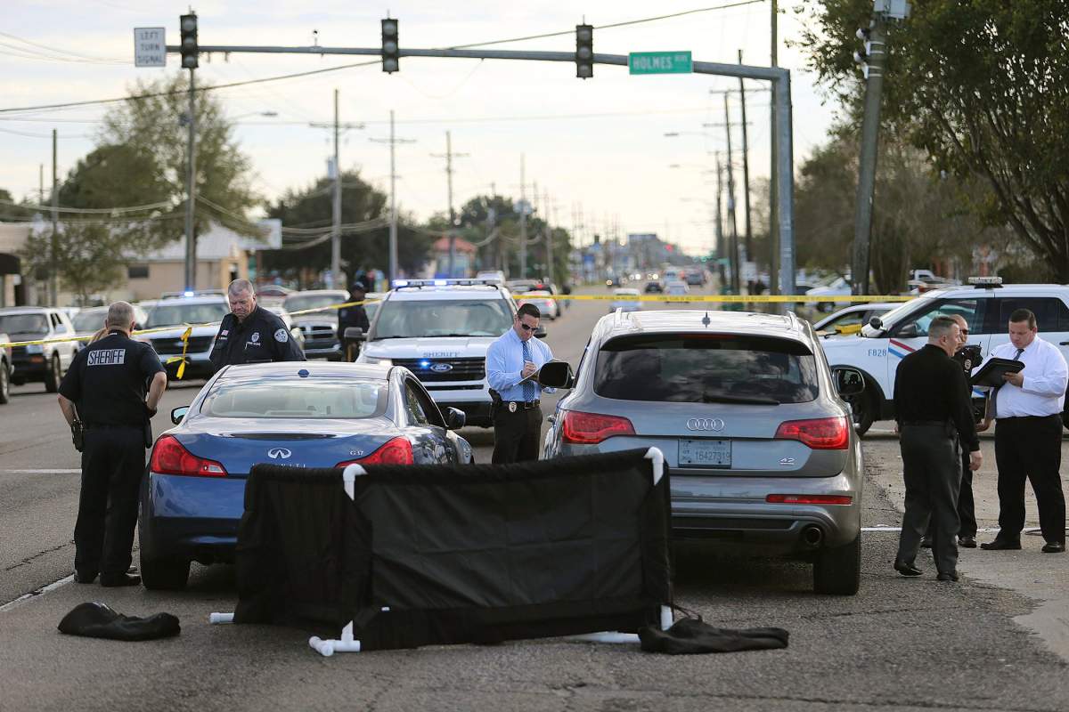 The body of former NFL player Joe McKnight lies between the shooter’s vehicle at left and his Audi SUV at right as the Jefferson Parish Sheriff’s Office investigates the scene in Terrytown, La., on Thursday, Dec. 1, 2016.