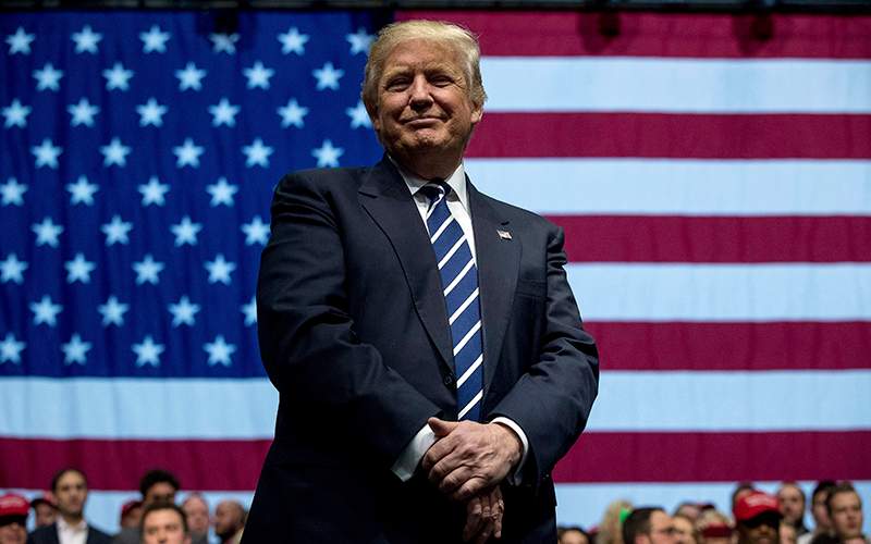 President-elect Donald Trump smiles as he listens to his pick for Education Secretary Betsy DeVos speak during a rally at DeltaPlex Arena, Friday, Dec. 9, 2016, in Grand Rapids, Mich. 