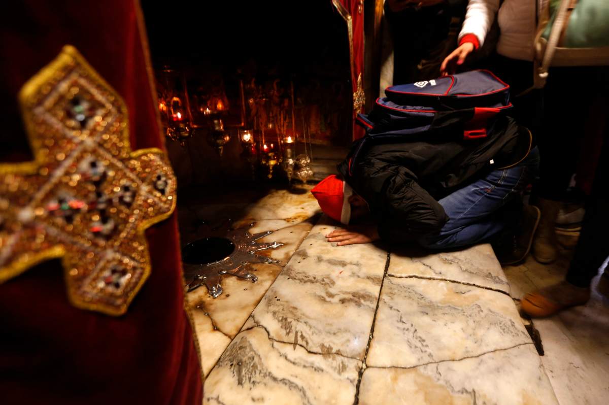 A Christian worshiper kisses the ground near the silver star which marks the place where it is believed Jesus Christ was born, in the Grotto at the Church of the Nativity, in the West Bank City of Bethlehem, Saturday, Dec. 24, 2016.
