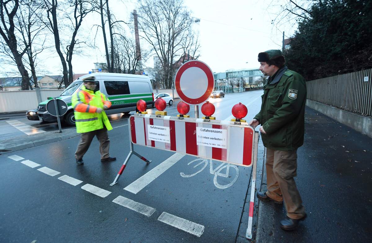 Policemen have blocked a road in Augsburg, Germany, Sunday, Dec. 25, 2016. Thousands of people in the German town of Augsburg have temporarily left Christmas presents and decorations behind while authorities disarm a World War II bomb. The bomb was uncovered last week during construction work.